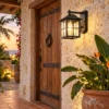 Black grid glass wall lantern beside a teak door on a coral-stone wall