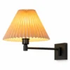 Black swing arm wall sconce with apricot pleated shade