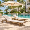 Teak sun loungers, side table and umbrella on a hotel pool deck